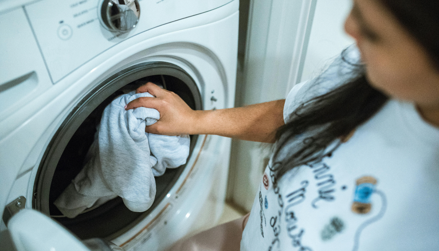 Mulher colocando roupa na máquina de lavar. (Crédito: Pexels/RDNE Stock project)