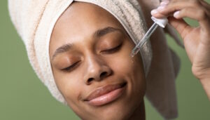 Mulher passando produto no rosto (Crédito: Freepik)