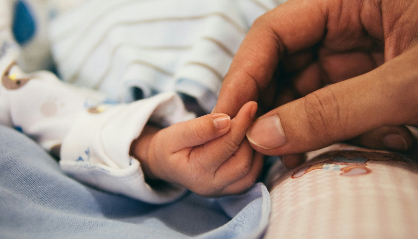 Adulto segurando a mão de um bebê recém-nascido