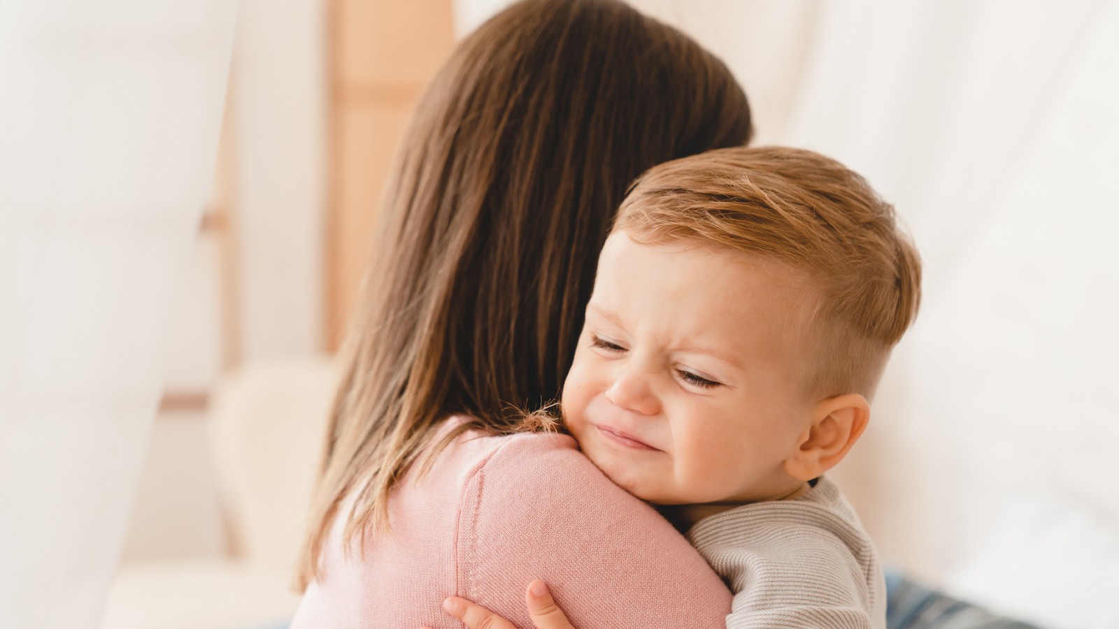 Mãe consola filho pequeno no colo